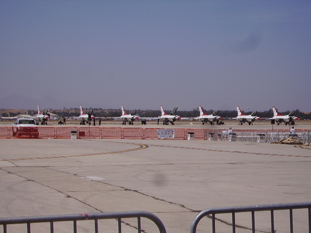 Fighter jets parked on an airfield with a white Ford Bronco in the foreground.