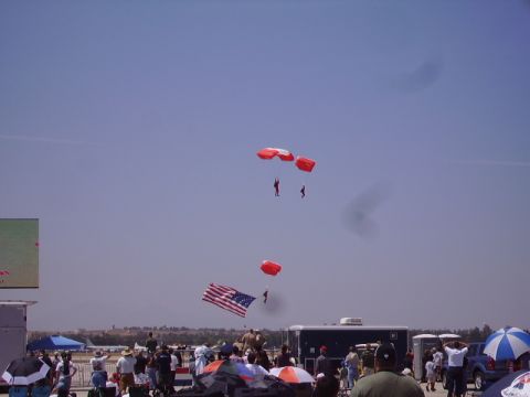1990 Ford Bronco - Multiple parachutists are seen in mid-air against a bright blue sky.