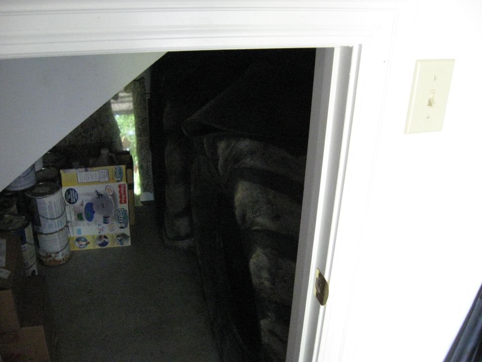 Interior view of a room with paint cans, a box, and furniture partially visible
