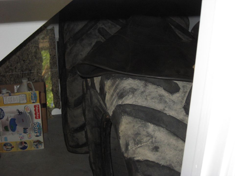 Several large tractor tires stacked up, with a Fisher-Price potty training seat box nearby