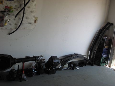 2006 Ford F-150 - Various vehicle parts, such as axles and leaf springs, are organized and stored in a garage setting.
