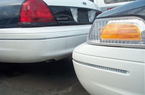 2001 Ford Crown Victoria - Close-up of the rear and front corners of two police vehicles parked side-by-side.