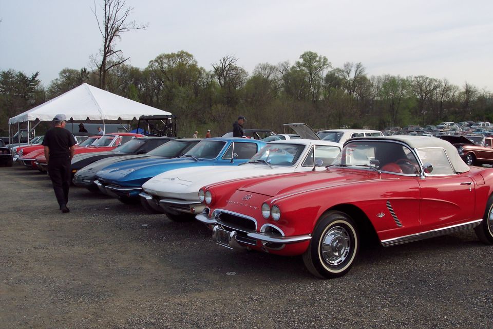 Several classic Corvettes parked in a line, with a red convertible in the foreground.