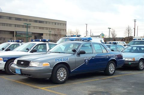 2001 Ford Crown Victoria - Two-tone silver and blue Ford Crown Victoria police cruiser marked "POLICE" with a shield door decal, blue Whelen-style light bar and hubca…