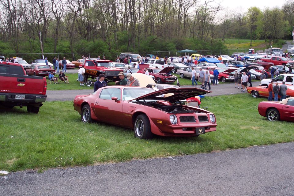 Red 1970s Pontiac Firebird Trans Am with hood open at a car show.