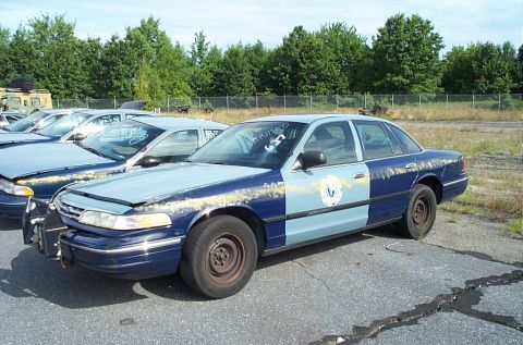2001 Ford Crown Victoria - A two-tone blue and light blue 2001 Ford Crown Victoria is parked in an outdoor lot with other vehicles.