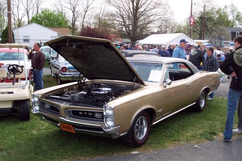 2001 Ford Crown Victoria - A classic 1967 Pontiac GTO is displayed with its hood open at a car show, surrounded by spectators and other vehicles.