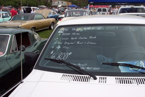 2001 Ford Crown Victoria - Handwritten notes on a windshield detail a 1991 Mazda B2200 SE for sale at an outdoor car show.