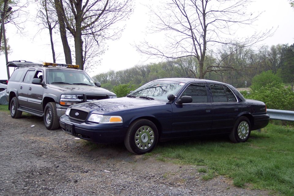 Dark blue 2001 Ford Crown Victoria sedan parked next to a dark SUV