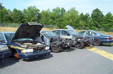 2001 Ford Crown Victoria - Multiple cars are lined up, some missing front-end components and engines.