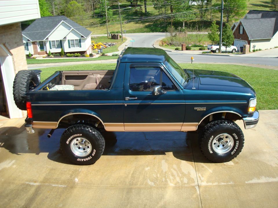Dark green 1995 Ford Bronco side view with tan trim and spare tire