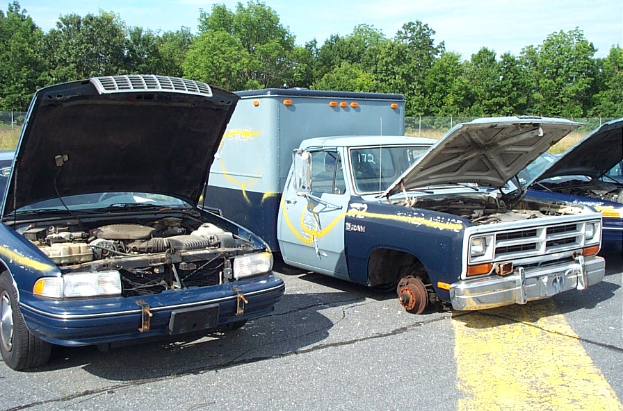 Blue sedan and a blue pickup truck with utility box, hoods up, parked outside