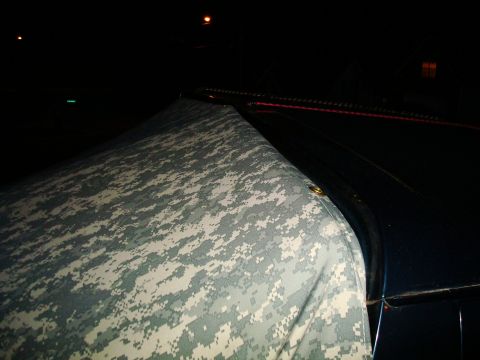 1995 Ford Bronco - A vehicle is covered with a camouflage tarp at night, with the Supermotors.net logo visible.