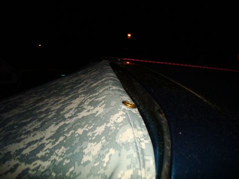 1995 Ford Bronco - A close-up view of a vehicle's soft top covered in camouflage fabric at night.