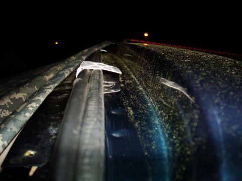 1995 Ford Bronco - A close-up view of the top of a dark blue vehicle with a camouflage soft top, taken at night.