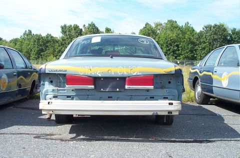 2001 Ford Crown Victoria - Rear view of a 2001 Ford Crown Victoria police car with visible 'STATE POLICE' text and missing body panels.