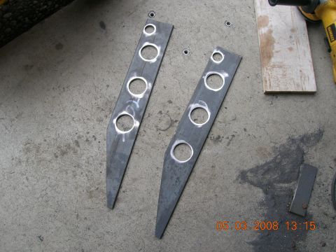 1996 Ford Bronco - Two custom metal brackets with holes drilled into them sit on a concrete surface.