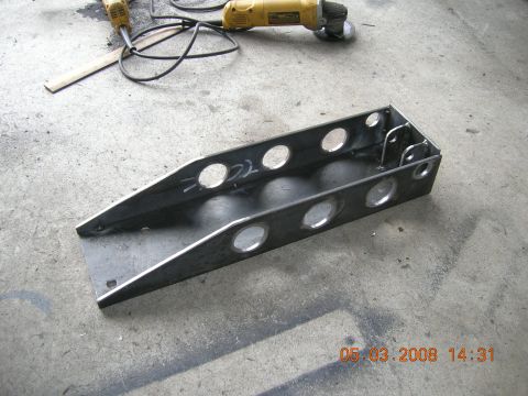 1996 Ford Bronco - A metal bracket with multiple circular cutouts sits on a concrete floor next to tools.