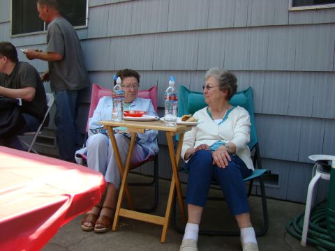 1989 Ford Bronco - People enjoy a casual outdoor gathering, with food and drinks laid out on a folding table.