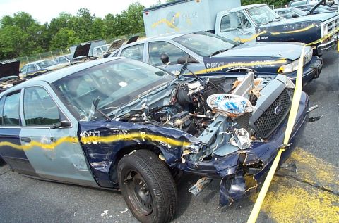 2001 Ford Crown Victoria - A wrecked 2001 Ford Crown Victoria police car sits in a lot with other vehicles.