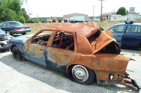 2001 Ford Crown Victoria - This heavily damaged 2001 Ford Crown Victoria shows extensive fire damage and is parked outdoors.