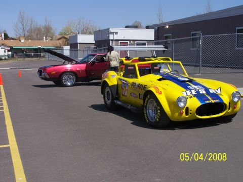 1972 Ford Ranchero - Two cars are parked on asphalt, one red and one yellow race car with sponsor decals.