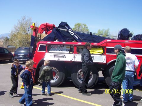 1972 Ford Ranchero - A large red tow truck is parked outside with several people observing it on a sunny day.