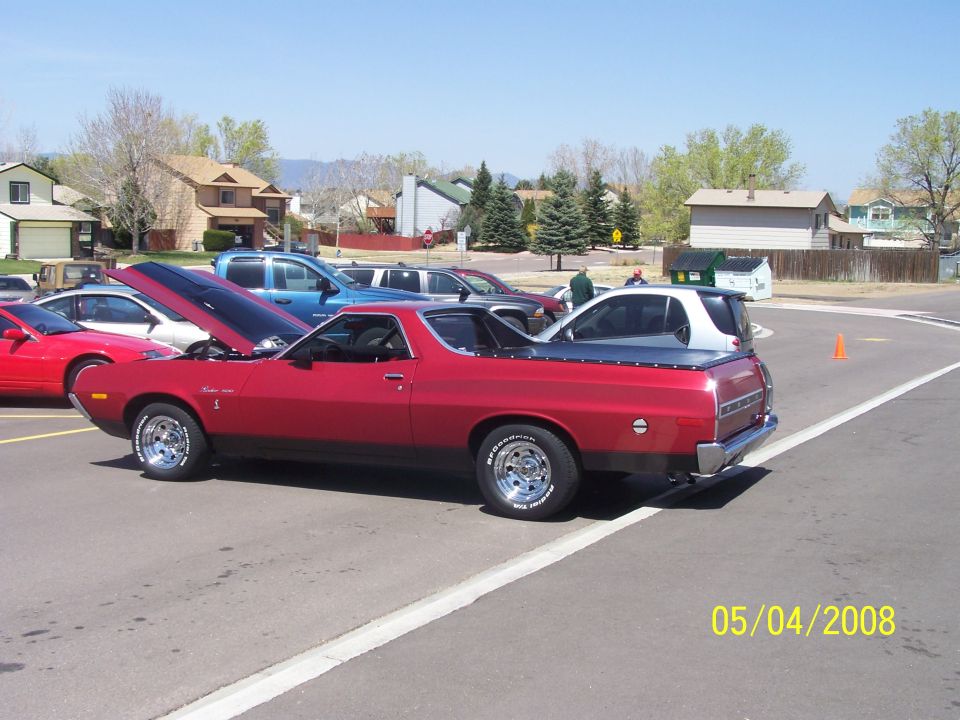 Red 1972 Ford Ranchero parked with hood open, other cars and houses in background