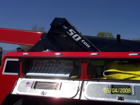 1972 Ford Ranchero - A tow truck features a prominent 50-ton crane and a detailed control panel, with an American flag emblem visible on its side.