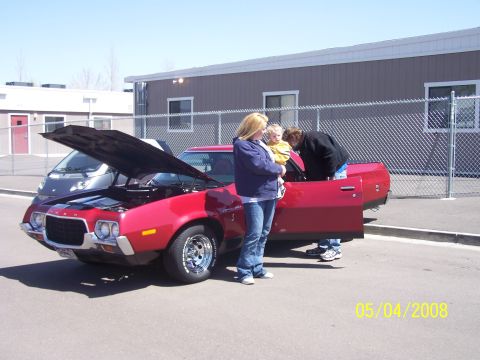 1972 Ford Ranchero - A red 1972 Ford Ranchero is displayed with its hood open, attracting attention from onlookers.