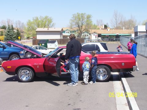 1972 Ford Ranchero - A red 1972 Ford Ranchero is displayed with its hood and door open, attracting attention from onlookers.