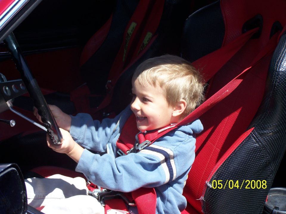 Child in racing seat with steering wheel, 05/04/2008 date stamp