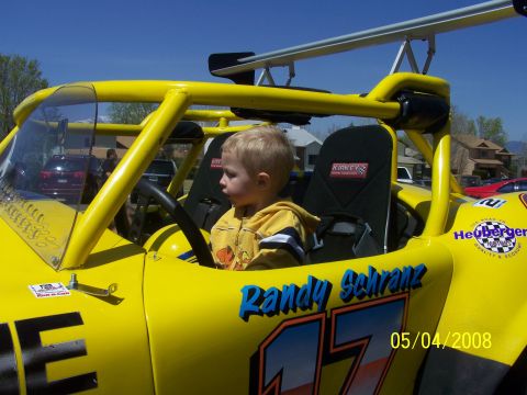 1972 Ford Ranchero - A young boy sits in the driver's seat of a bright yellow racing vehicle, with racing decals visible.