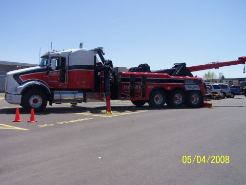 1972 Ford Ranchero - A red and white tow truck is parked in a lot with other vehicles visible in the background.
