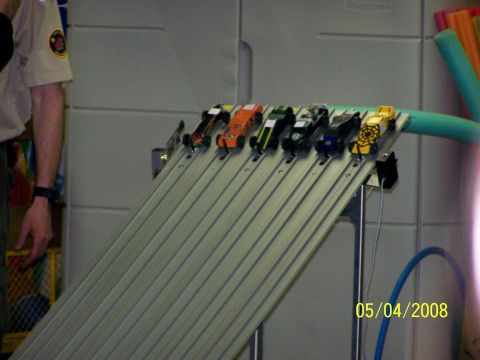 1972 Ford Ranchero - Several toy cars are lined up on a multi-lane ramp, ready for a race.