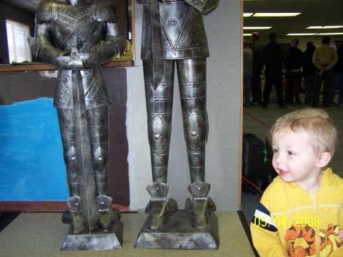 1972 Ford Ranchero - A young child observes two full suits of knight armor, with other people visible in the background.