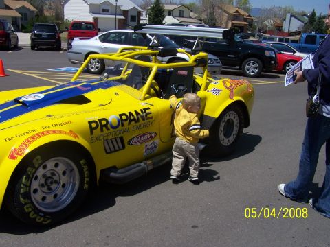 1972 Ford Ranchero - A child stands next to a yellow custom race car with racing decals and a roll cage.