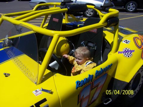 1972 Ford Ranchero - A young child sits in the driver's seat of a bright yellow racing go-kart.