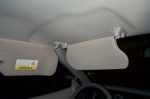 2001 Ford Crown Victoria - The interior of a car shows two sun visors, one with a warning label.