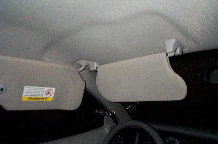 Interior view of two beige sun visors, one with a yellow warning sticker