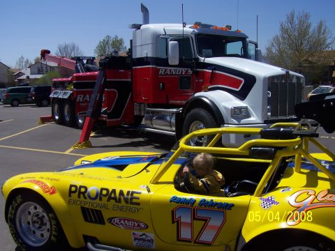 1972 Ford Ranchero - A child sits in a yellow race car, parked in front of a large tow truck.