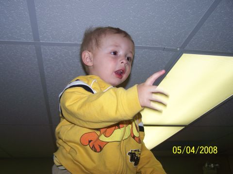 1972 Ford Ranchero - A young child in a yellow hoodie reaches out towards a ceiling light.