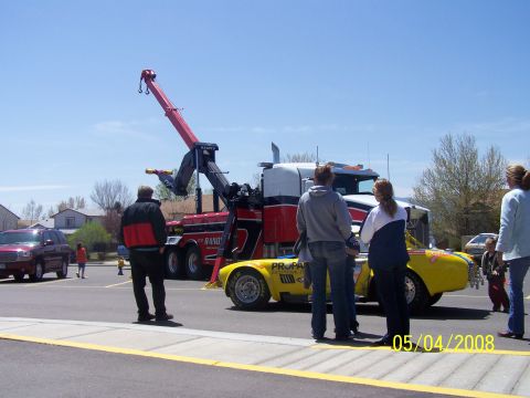 1972 Ford Ranchero - A tow truck is parked next to a yellow race car. Several people are standing around observing.