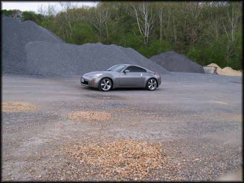 2003 Nissan 350Z - A silver 2003 Nissan 350Z is parked on a gravel lot with large piles of construction aggregate behind it.