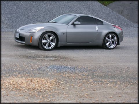 2003 Nissan 350Z - A silver 2003 Nissan 350Z coupe is shown from a three-quarter front angle, parked outdoors on a gravel surface.