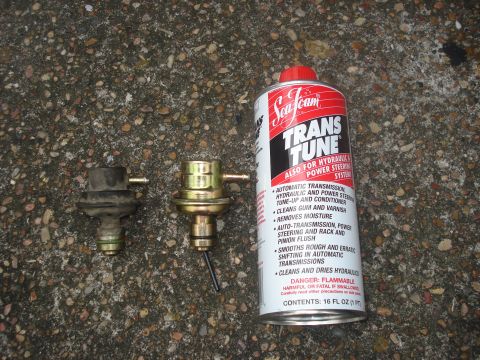 1989 Ford Bronco II - Two vacuum modulators and a can of Sea Foam Trans Tune are laid out on a gravel surface.