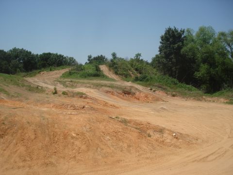 1989 Ford Bronco II - A dirt track with tire marks and vegetation under a clear blue sky, suitable for off-road vehicles.