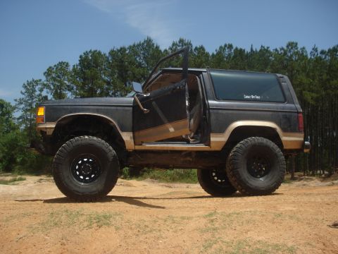 1989 Ford Bronco II - A lifted 1989 Ford Bronco II sits off-road with its driver's door ajar.