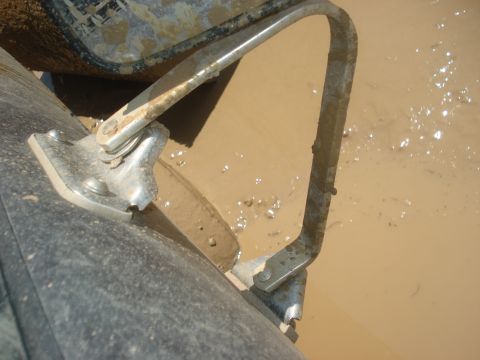 1989 Ford Bronco II - Metal bracket and tire submerged in mud, suggesting off-road activity.