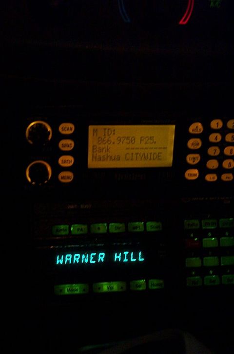 2001 Ford Crown Victoria - A scanner radio display shows 'WARNER HILL' and programming information including an ID and bank name.
